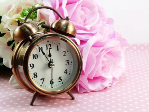 Spring time with alarm clock and artificial flowers bouquet background Foto stock