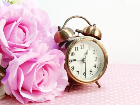 Spring time with alarm clock and artificial flowers bouquet background Stockfoto's