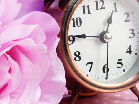 Spring time with alarm clock and artificial flowers bouquet background 写真素材