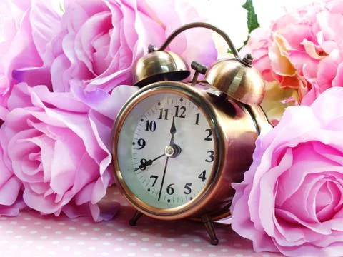 Spring time with alarm clock and artificial flowers bouquet background 库存照片