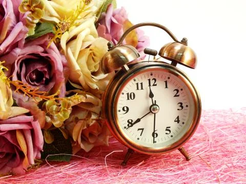 Spring time with alarm clock and artificial flowers bouquet background Stockfoto's