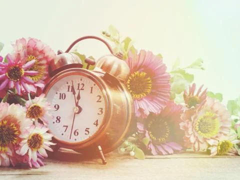 Spring time with alarm clock and artificial flowers bouquet background Stockfoto's