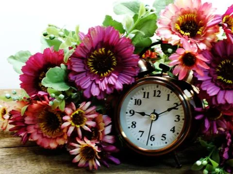 Spring time with alarm clock and artificial flowers bouquet background 写真素材