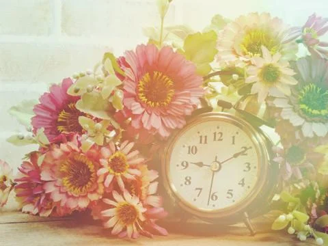 Spring time with alarm clock and artificial flowers bouquet background Stockfoto's