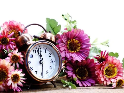 Spring time with alarm clock and artificial flowers bouquet background 写真素材