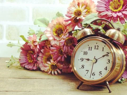 Spring time with alarm clock and artificial flowers bouquet background 스톡 사진
