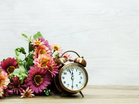 Spring time with alarm clock and artificial flowers bouquet background Foto stock