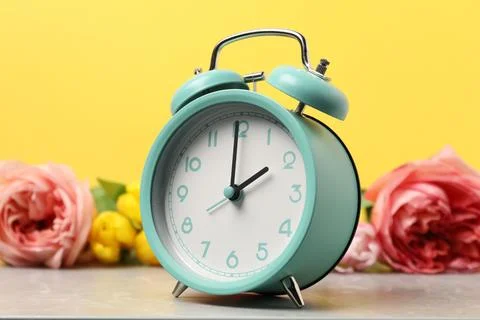 Spring time. Alarm clock and beautiful flowers on grey marble table against.. 写真素材