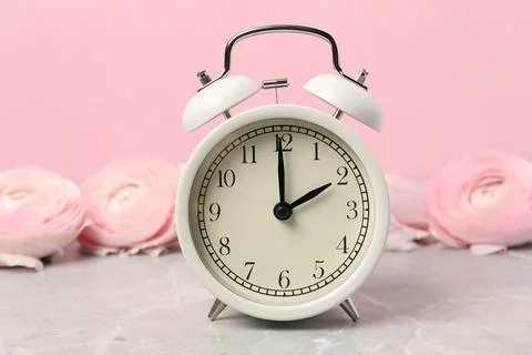 Spring time. Alarm clock and beautiful ranunculus flowers on grey marble ta.. Foto stock