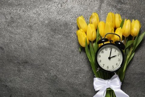 Spring time. Alarm clock and beautiful tulips on grey table, flat lay. Spac.. 写真素材