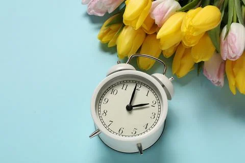 Spring time. Alarm clock and beautiful tulips on light blue background, abo.. 写真素材