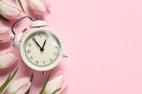 Spring time. Alarm clock and beautiful tulips on pink background, flat lay... Foto stock