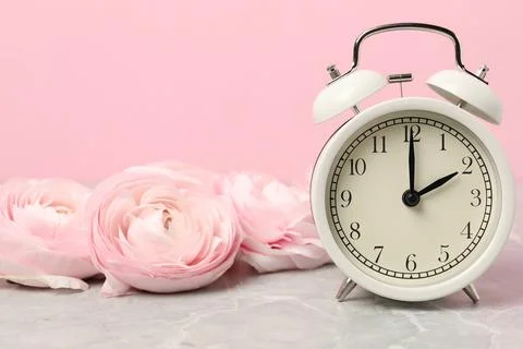 Spring time. Alarm clock and beautiful ranunculus flowers on grey marble ta.. Stock Photos