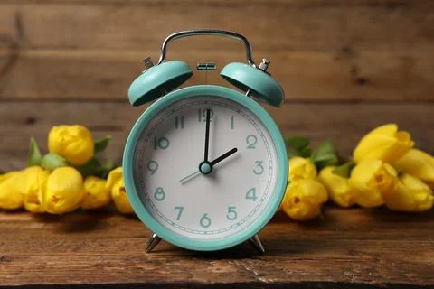 Spring time. Alarm clock and beautiful tulips on wooden table 写真素材