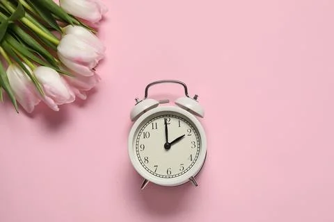 Spring time. Alarm clock and beautiful tulips on pink background, flat lay 스톡 사진