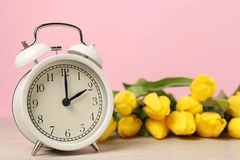 Spring time. Alarm clock and beautiful tulips on wooden table against pink .. 写真素材