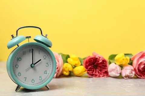 Spring time. Alarm clock and beautiful flowers on grey marble table against.. 写真素材