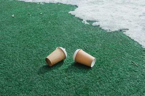 In the spring, two empty coffee cups were thrown onto a green plastic floor i 스톡 사진