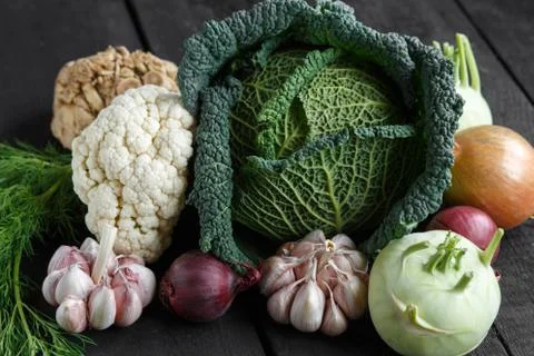 Spring vegetables on a dark background: Savoy cabbage, cauliflower, onion Stock Photos