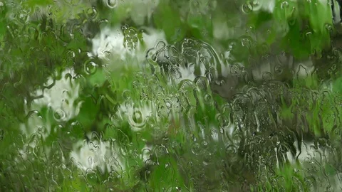 Spring view through rainy window. Water sprinkling on glass in slow motion. Stock Footage 90566546
