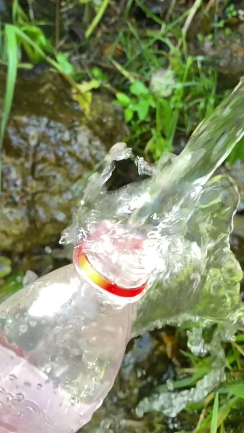Spring water flows into a bottle. flying splashes of water Video stock 205047563