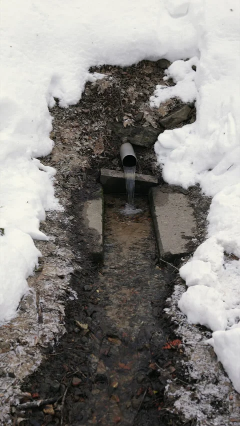 A spring water flows through a snowy park 库存影片 263664694