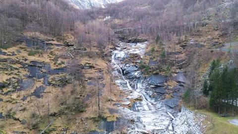 Spring waterfall cascading down rocky slopes in a scenic mountain landscape 스톡 동영상 303516397