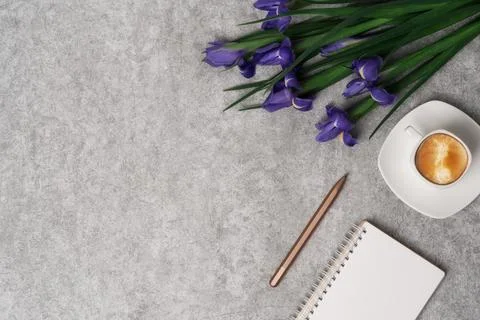 Spring women's workspace top view with beautiful iris flowers, laptop, notepad Stock Photos