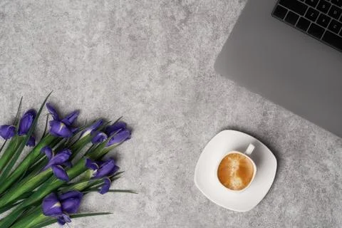 Spring women's workspace top view with beautiful iris flowers, laptop and coffee Stock Photos