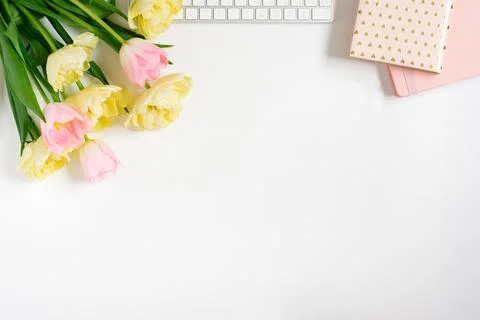 Springtime flat fly with keyboard, notebooks, bunch of pink tulips on a light Stock Photos