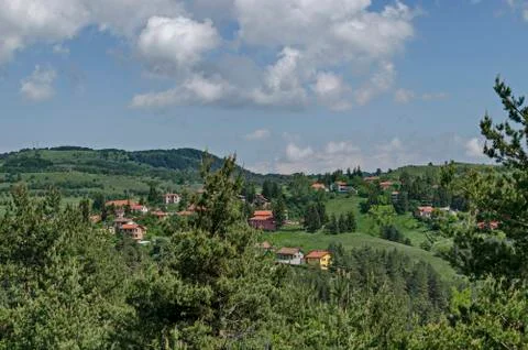 Springtime scene with mountain glade, forest and residential district Stock Photos
