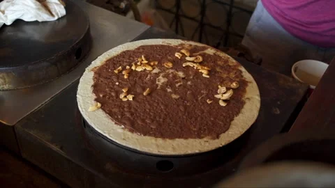 Sprinkle cashew nuts onto crispy crepes spread with Nutella on the crepe sto Stock Footage 277427310