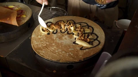Sprinkle cashew nuts onto crispy crepes filled with bananas on the crepe sto Stock Footage 278705376
