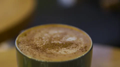 Sprinkle cinnamon on coffee Sprinkling coffee foam with cinnamon powder in a cup Stock Footage 293576998
