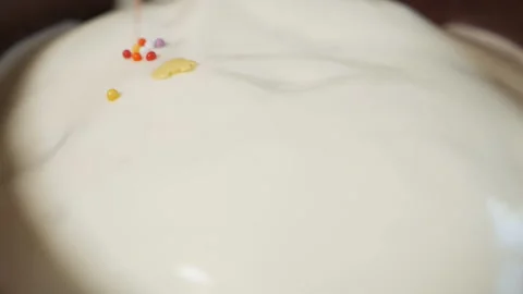 Sprinkle Easter cakes with sprinkles. On sweet glazed white Easter cakes pour Stock Footage 130877536