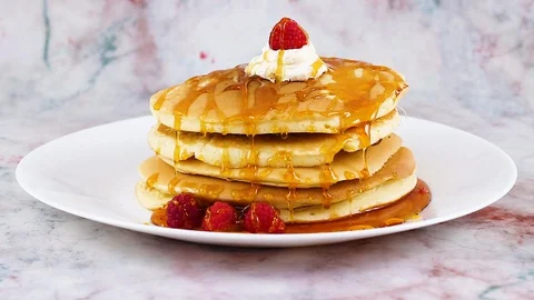 Sprinkle pancakes with cut nuts. Delicious pancakes with maple syrup and nuts Vidéo 128993722