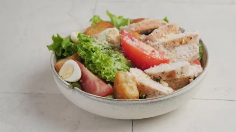 Sprinkle parmesan cheese in a plate with Caesar chicken salad Stock Footage 220481484