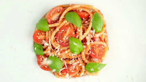 Sprinkle parmesan cheese on spaghetti with tomatoes, basil leaves top view Stock Footage 237058023