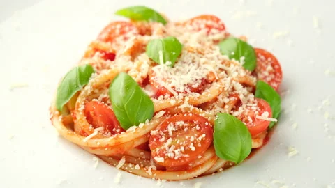 Sprinkle parmesan cheese on spaghetti with tomatoes, basil leaves top view Stock Footage 237058997