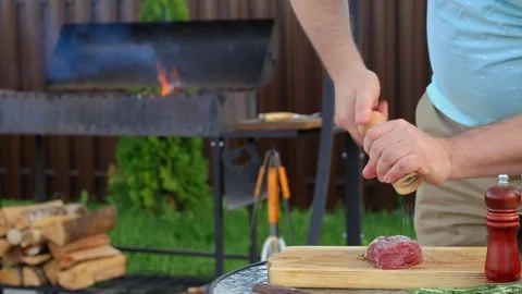 Sprinkle salt from hand grinder on raw strip steak Stock Footage 250444247