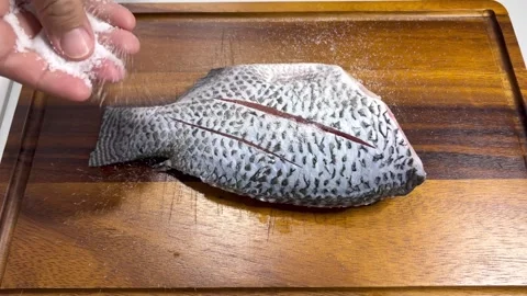 Sprinkle salt on tilapia2 Stock Footage 338216820