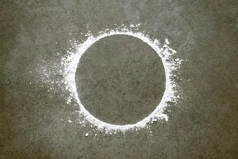 Sprinkled wheat flour circle on stone background. Baking and cooking dough .. Stock Photos