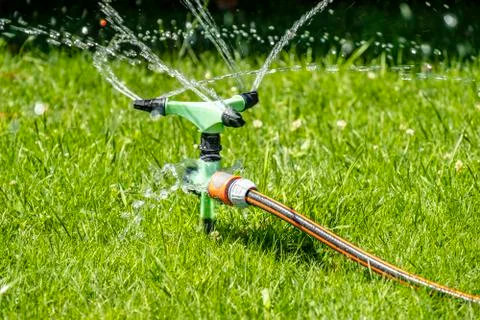 Sprinkler of automatic watering system working in the hot summer Stock Photos