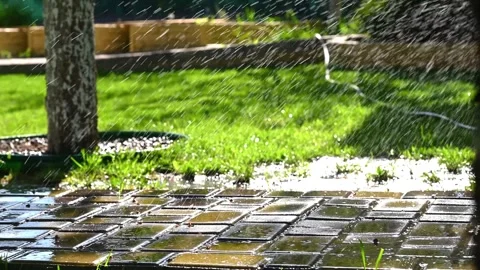 Sprinkler drops fall on stone pavement in backyard. Stock Footage 344552274