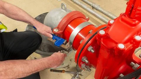 Sprinkler engineer checking water supply pump on a red valve set Stock Photos