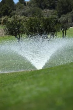 Sprinkler on a golf course Stock Photos