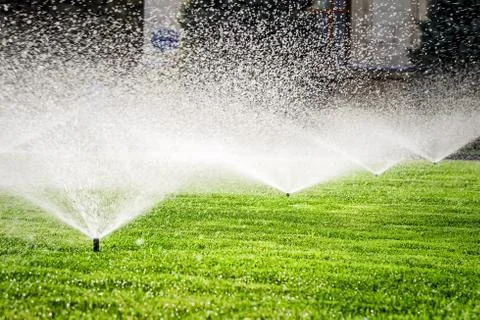Sprinkler on the grass field Stock Photos