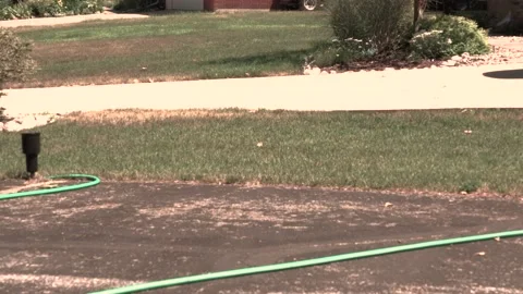 Sprinkler opening up to water a slim patch of grass. Sepia tones. Video stock 138515830