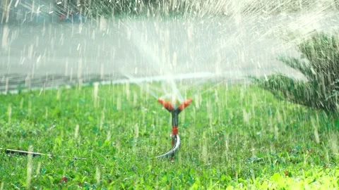 The sprinkler spins in different directions and generously waters the lawn Stock Footage 286340887