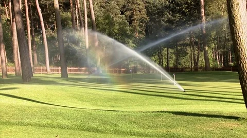 Sprinklers on a golf course cause a rainbow effect 库存影片 80509783